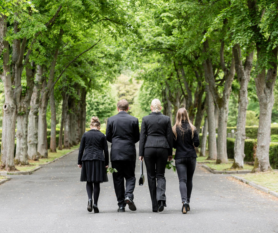 photo of 4 adults in black walking down a tree-lined path after a funeral | Overnight Caskets | Buying a Casket Online