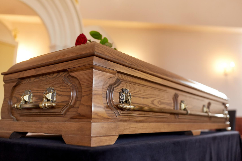 image of a wood casket with roses on top | Funeral Planning Secrets | Overnight Caskets 