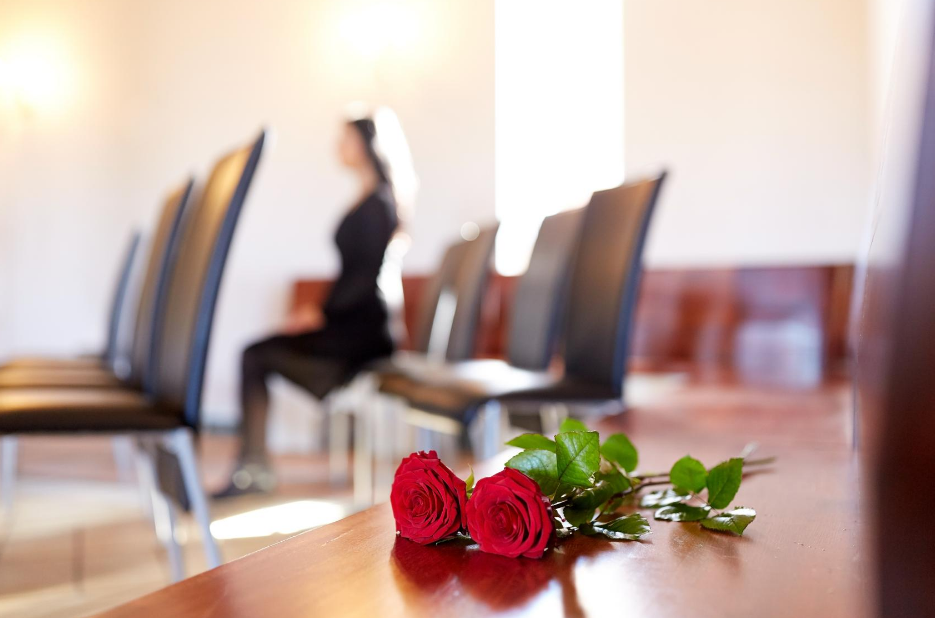 woman sitting near casket with roses on it | Buy a casket online | Overnight Caskets